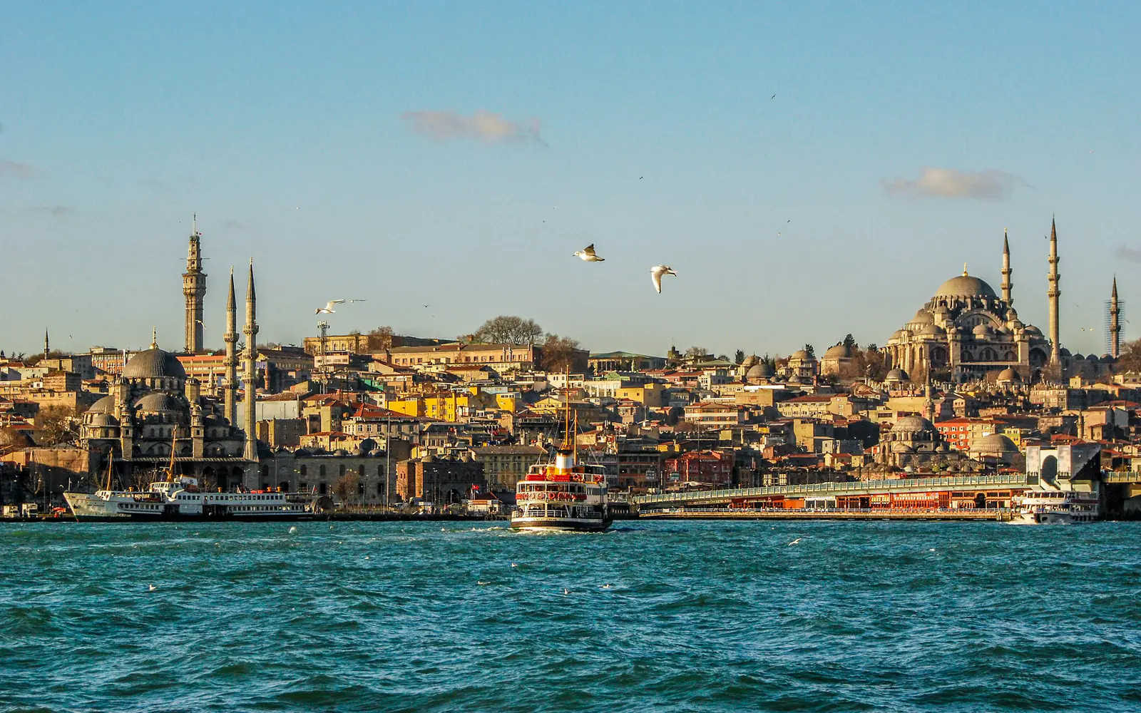 A ferry crosses the water in Istanbul with the domes and minarets of Eminönü on the skyline.