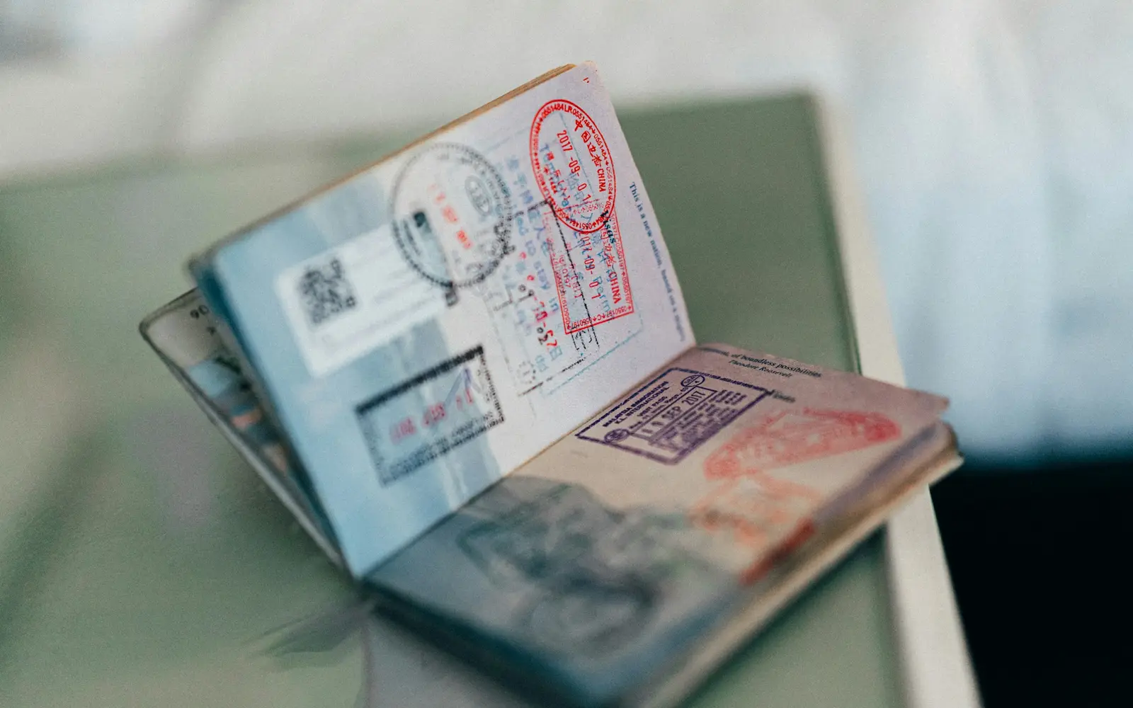 An open passport with colourful visa and entry stamps on its pages.