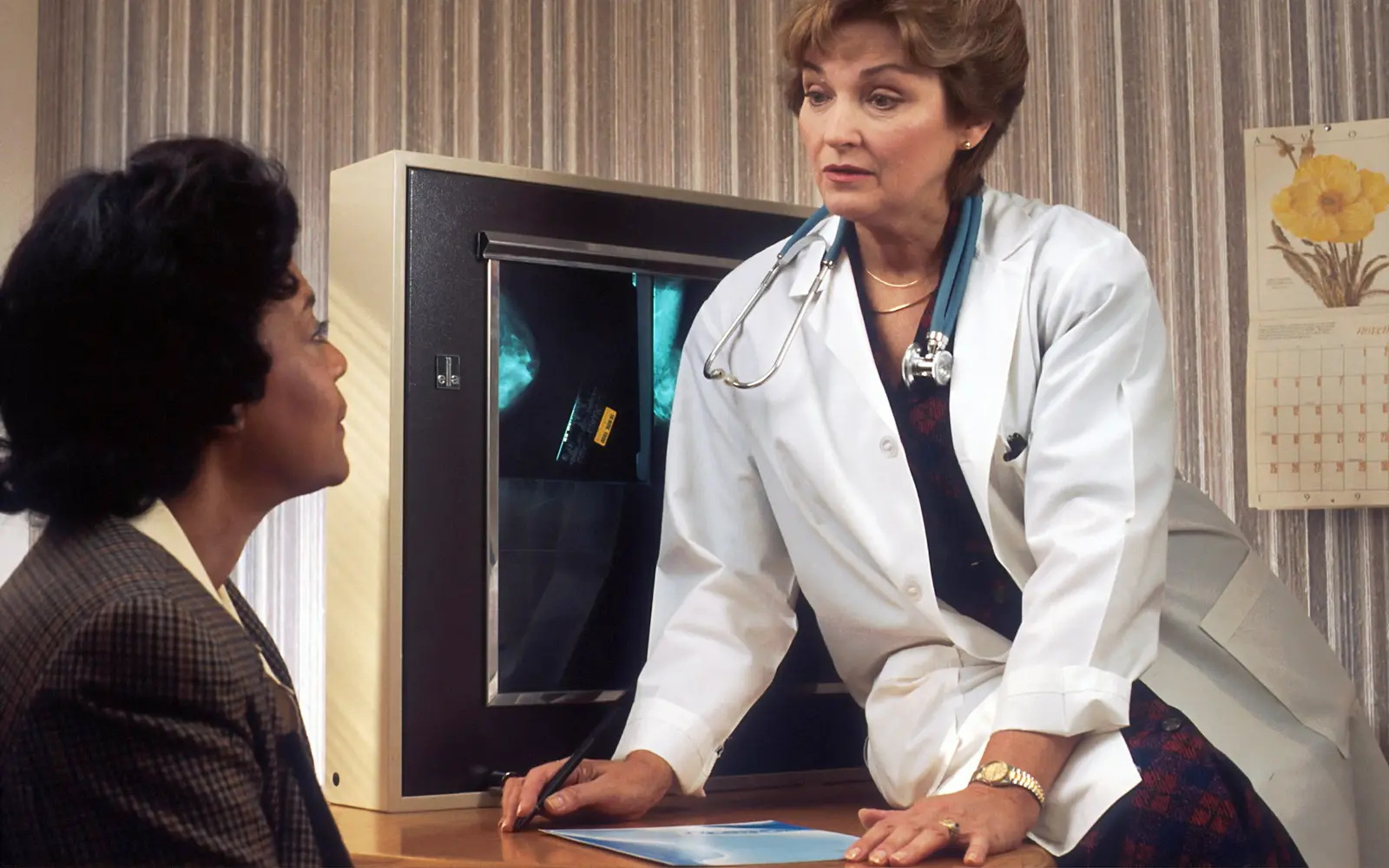 A doctor shows a patient her mammogram films on a lightbox during a consultation