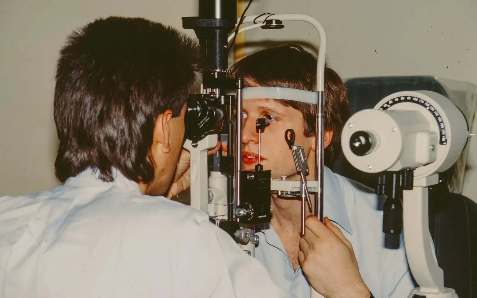 An eye specialist examines a patient's eye using a slit lamp.